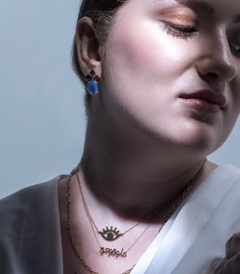 woman under the light wearing an earring and three necklaces inspired from the arab culture